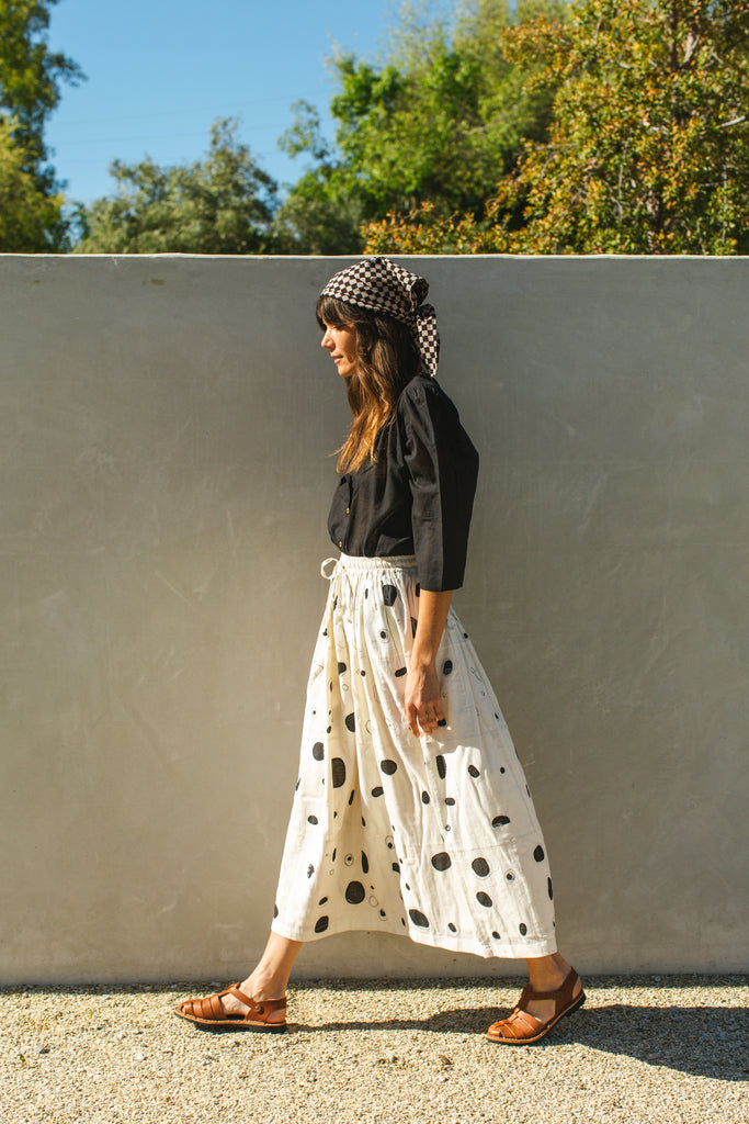 This Raindrops skirt is meticulously crafted from hand-woven fabric. Its exquisite appliqué work adds a touch of enchantment, elevating any ensemble. With its timeless black and white palette, this skirt effortlessly complements a variety of tops and shirts, ensuring versatility and sophistication with every wear.