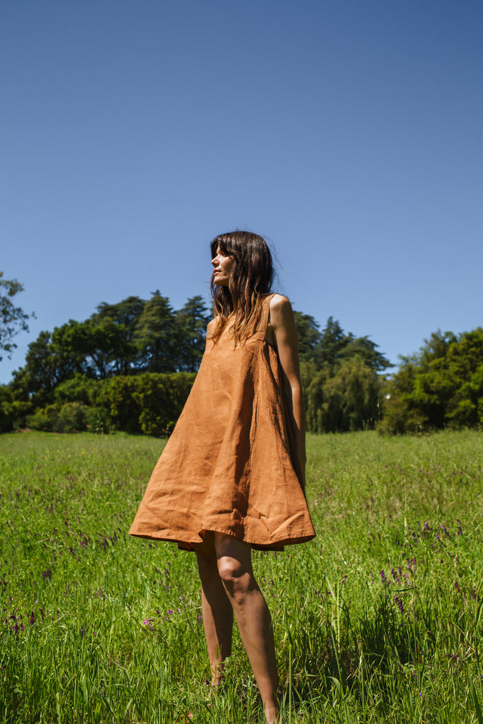 This noon dress is made in collaboration between Erica Kim and World of Crow, it has linen fabric, Brown rustic color, sleeveless, above knee-length dress, it is sustainably made and true to size