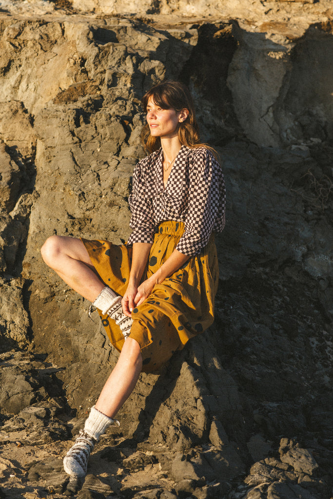 A black and white checkered blouse with a Victorian collar paired with a yellow skirt, showcasing vintage elegance.