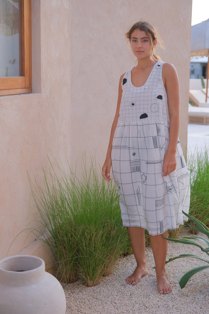 Introducing the Joan Check Dress, a collaboration between Audrey E Leary and World of Crow. This black and white midi-length dress features a refined mosaic pattern, a round V-neck, and is crafted from soft, handwoven cotton. Sustainably made with a relaxed fit and midweight fabric, it’s perfect for layering with the Artist Smock for a versatile look