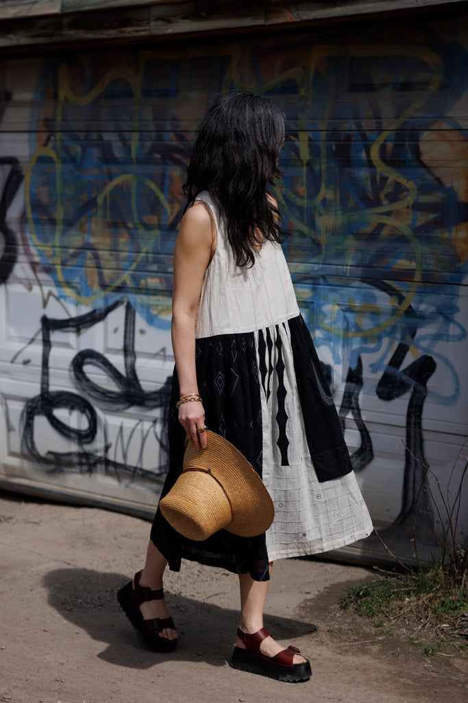 Introducing the Joan dress, a stunning piece in timeless black & white colour. Handwoven from cotton, it showcases intricate appliqué and patchwork detailing for a touch of artisanal charm. Featuring a flattering round V-neck and sleeveless design, this A-line dress offers both elegance and comfort. Complete with convenient side pockets and a midi-length silhouette, it's the epitome of effortless style for any occasion.