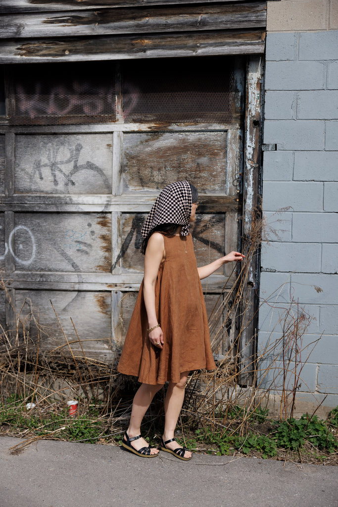 This noon dress is made in collaboration between Erica Kim and World of Crow, it has linen fabric, Brown rustic color, sleeveless, above knee-length dress, it is sustainably made and true to size