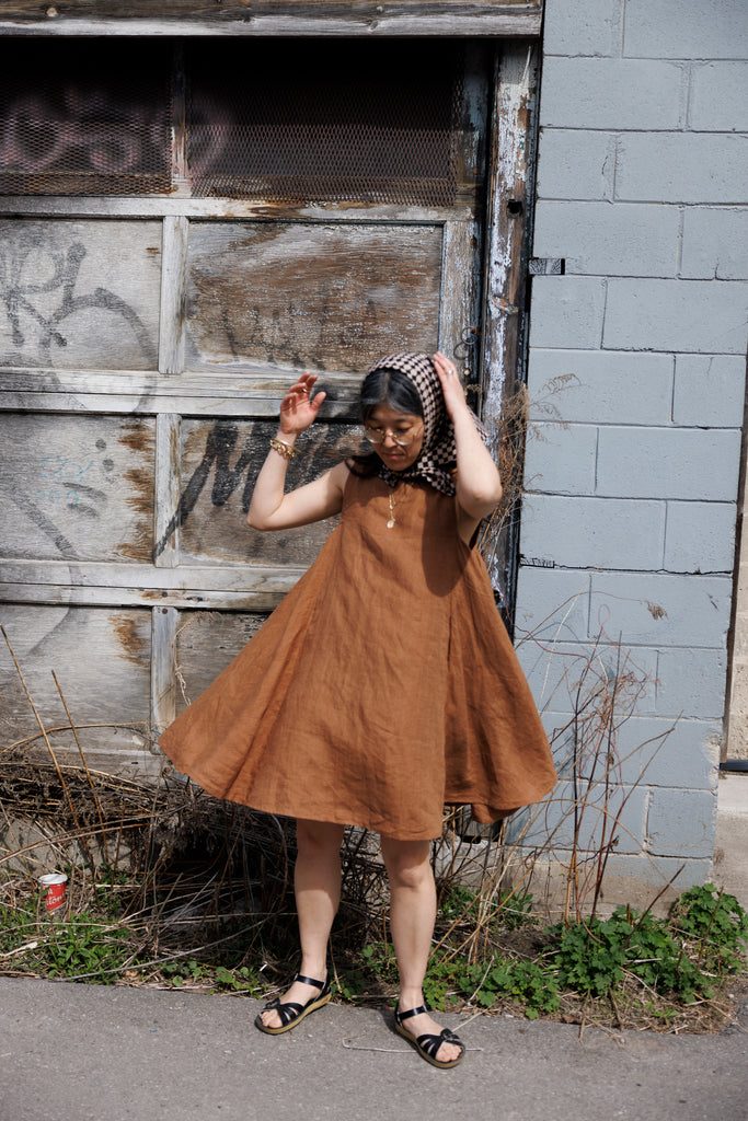 This noon dress is made in collaboration between Erica Kim and World of Crow, it has linen fabric, Brown rustic color, sleeveless, above knee-length dress, it is sustainably made and true to size