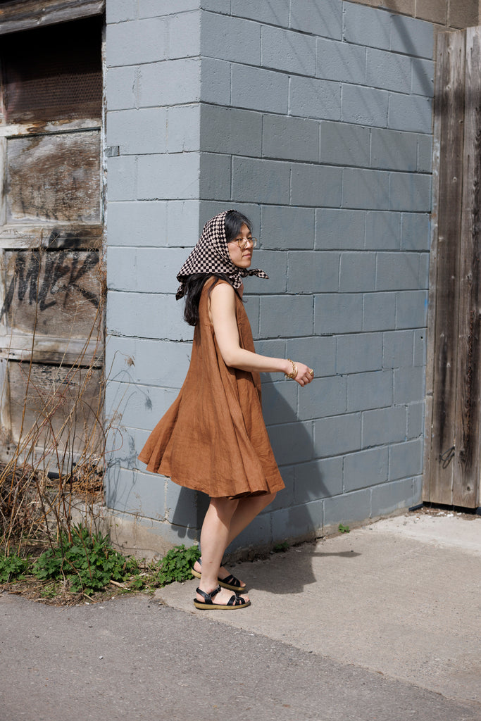 This noon dress is made in collaboration between Erica Kim and World of Crow, it has linen fabric, Brown rustic color, sleeveless, above knee-length dress, it is sustainably made and true to size