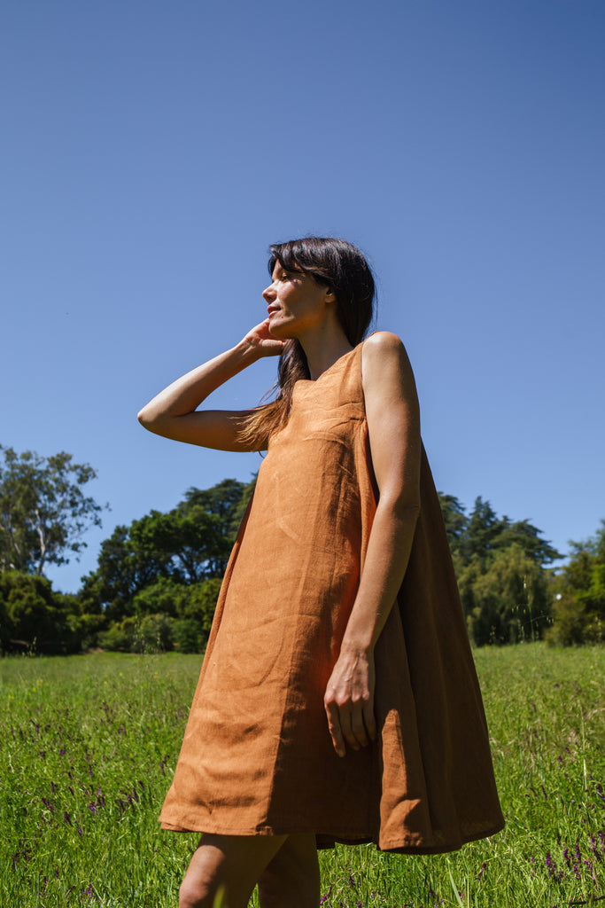 This noon dress is made in collaboration between Erica Kim and World of Crow, it has linen fabric, Brown rustic color, sleeveless, above knee-length dress, it is sustainably made and true to size