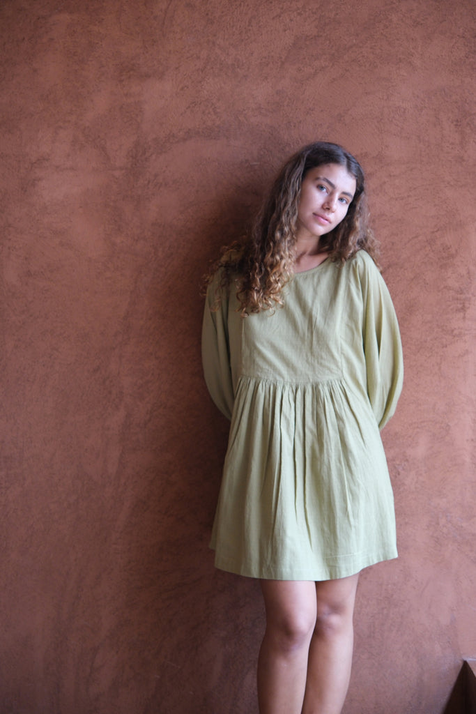 Introducing the Olive Get Away Dress, a collaboration between Audrey E Leary and World of Crow. This mini dress in unique olive green features a scoop neck and three-quarter puff sleeves, crafted from soft, handwoven cotton. Sustainably made and breathable, it offers a comfortable, true-to-size fit with lightweight, non-stretchy fabric, ideal for everyday wear.