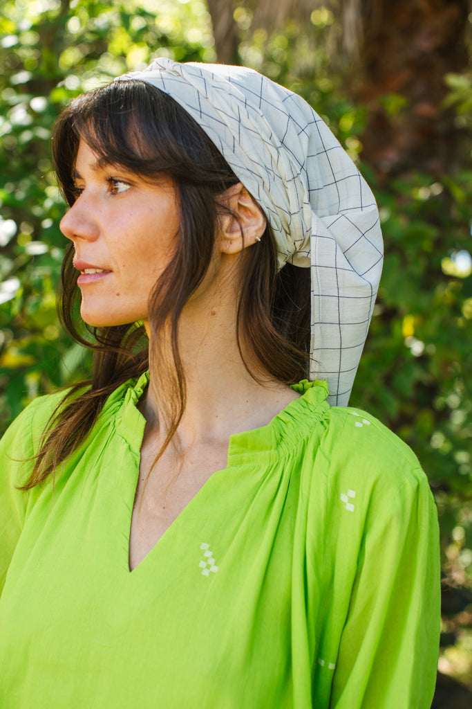 Introducing the Easy Checks Bandana, meticulously crafted from hand-woven cotton. Featuring a serene white base adorned with classic black checks, this versatile accessory offers timeless style. Wear it as a chic scarf, or tie it in your hair for a playful yet sophisticated look. Add a dash of elegance to any outfit with this must-have accessory.