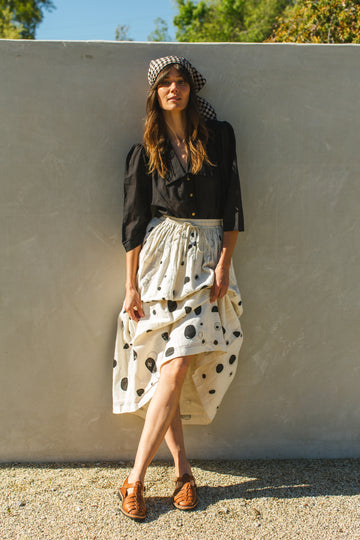 This Raindrops skirt is meticulously crafted from hand-woven fabric. Its exquisite appliqué work adds a touch of enchantment, elevating any ensemble. With its timeless black and white palette, this skirt effortlessly complements a variety of tops and shirts, ensuring versatility and sophistication with every wear.