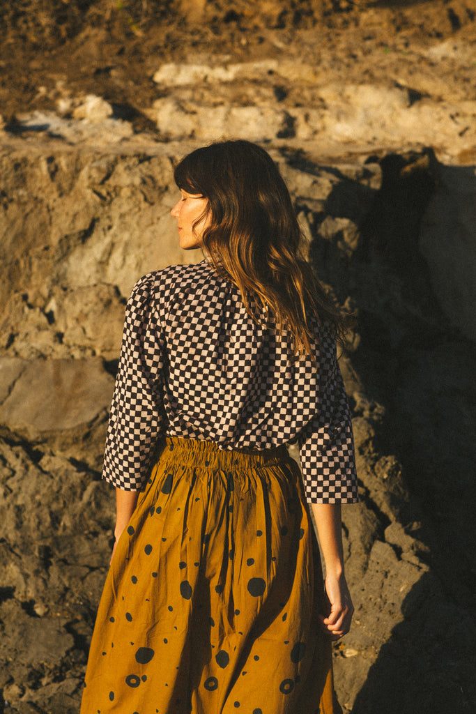 The Circles All Over Skirt features a striking brown and navy block print with circular patterns. Made from 100% handwoven cotton, it offers a comfortable mid-rise elasticated waistband and a chic mid-calf length, perfect for a polished yet relaxed style.