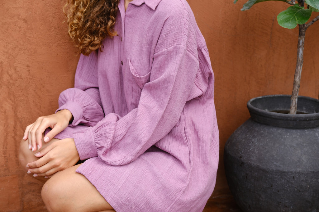 Introducing the Artist Smock, a collaboration between Audrey E Leary and World of Crow. This pink dual-tone smock is crafted from thick, handwoven organic cotton and features a straight collar, puff full sleeves, and spacious pockets. With a short length and gathered cuffs, it offers a comfortable fit and is perfect for painting, crafting, and staying cozy during travel.