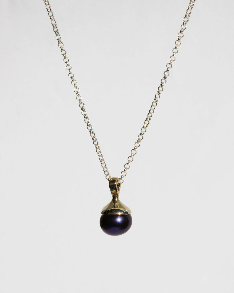 Introducing the sophisticated black pearl pendant, suspended on a classic sterling silver chain. This elegant piece features a lustrous black pearl that adds a touch of refinement to any ensemble. The pendant is available in both brass and sterling silver, and the chain is adjustable from 16" to 20" for a customizable fit.